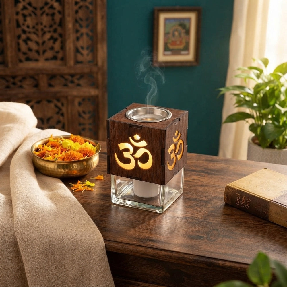 An electrical glass camphor diffuser emitting subtle steam on a wooden table with marigold petals and a cream linen cloth.