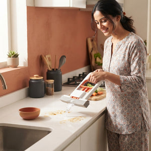 A woman using a mini foldable sponge mop to clean a kitchen countertop in a bright, modern home setting.